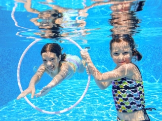 Happy active kids swim in pool and play underwater